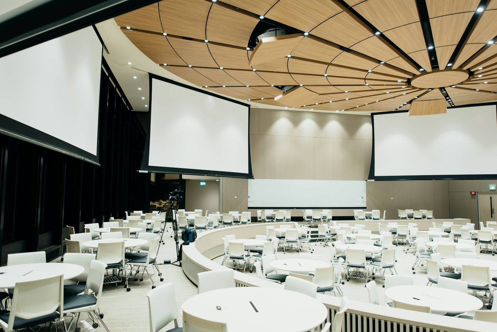 Salle de conférence avec tables rondes et écrans de projection